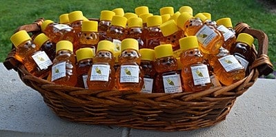 Bottles of honey in little bears in a basket image.
