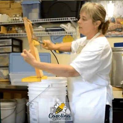 Beekeeper removing beeswax cappings from honey frame image.