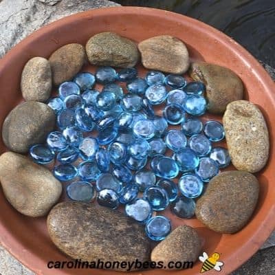 Natural river stone and glass stones in a clay dish for bee water image.