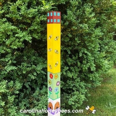 Wooden bee garden art pole decorated in bee theme for yard image.