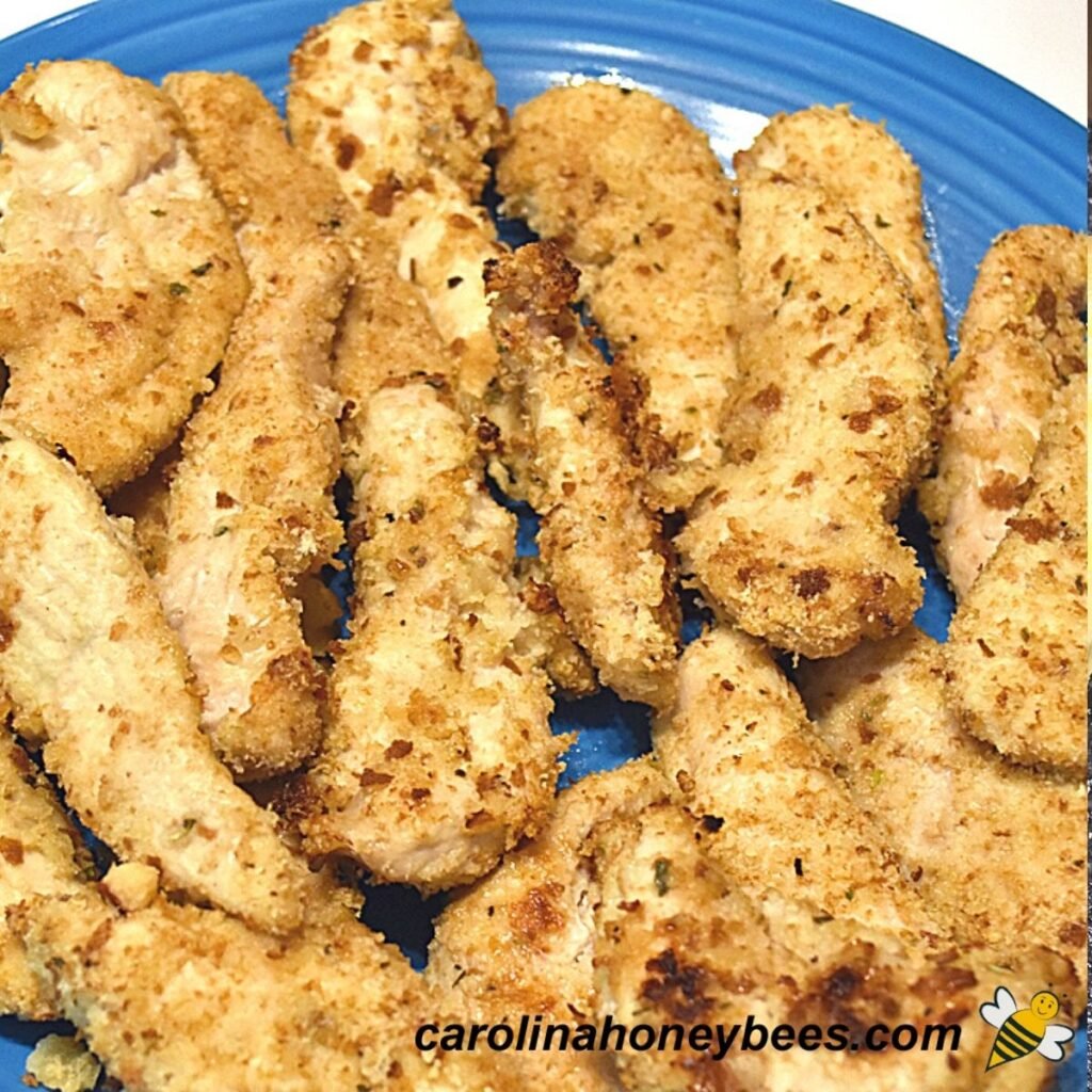 Baked honey chicken tenders with bread crust on plate image.