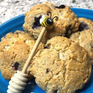 Homemade honey blueberry scones on a blue plate with bee dipper image.