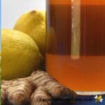 Jar of raw honey with lemons and ginger root ingredients for infusion image.