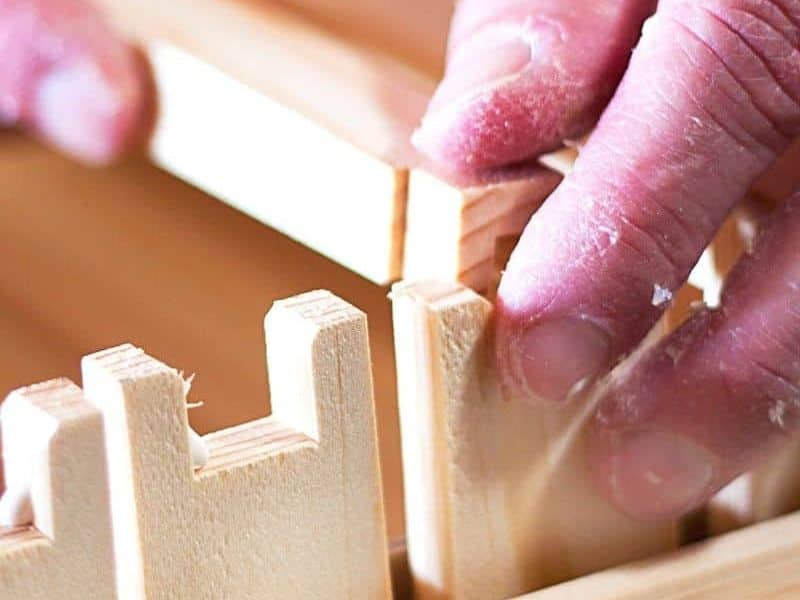 Beekeeper assembling parts of wooden frames for a hive image.