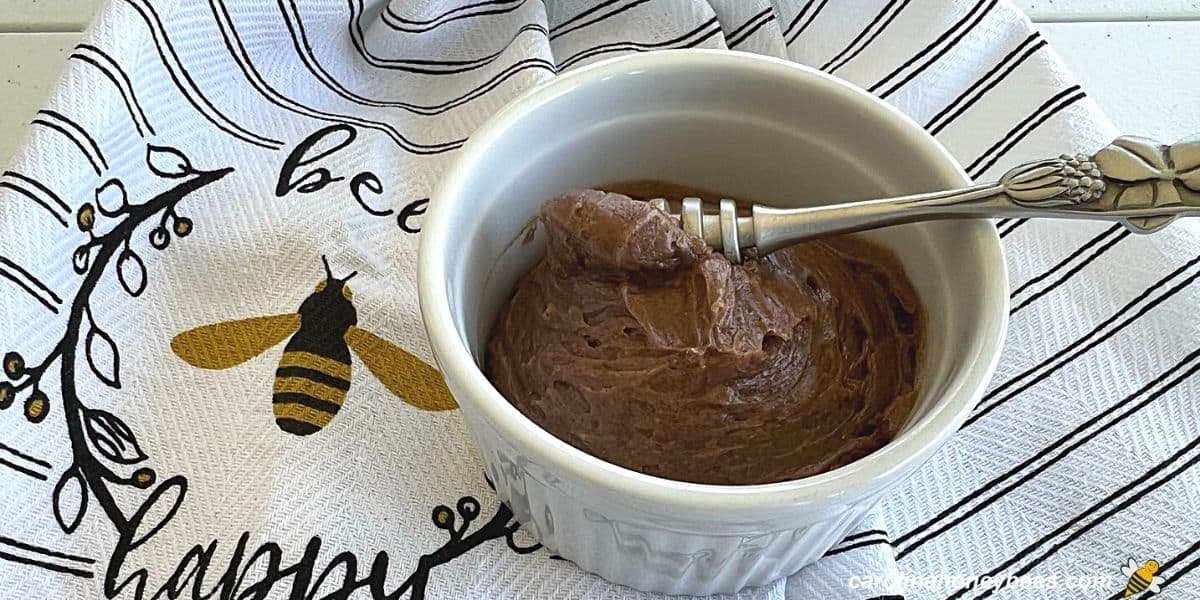 Homemade cinnamon honey butter in a white dish with a honey bee towel.