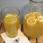 Pitcher and glass of honey sweetened lemonade with slices.