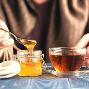 Mug of hot tea with honey jar.