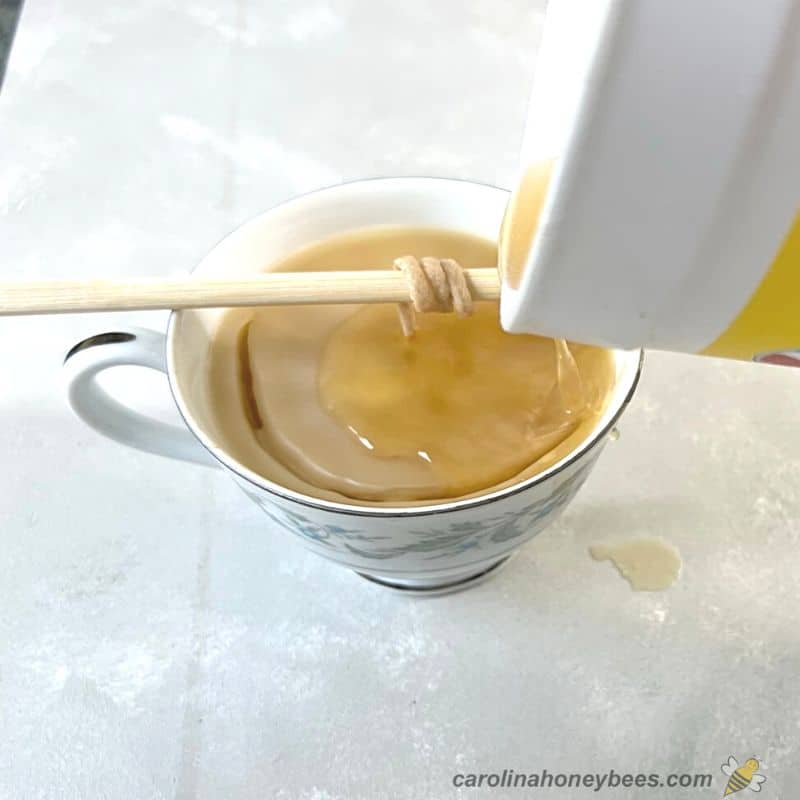 Pouring melted beeswax into cup to cover up cracked top.