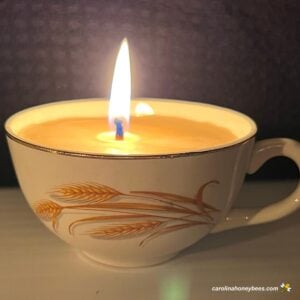 Lit beeswax candle in an old cup.