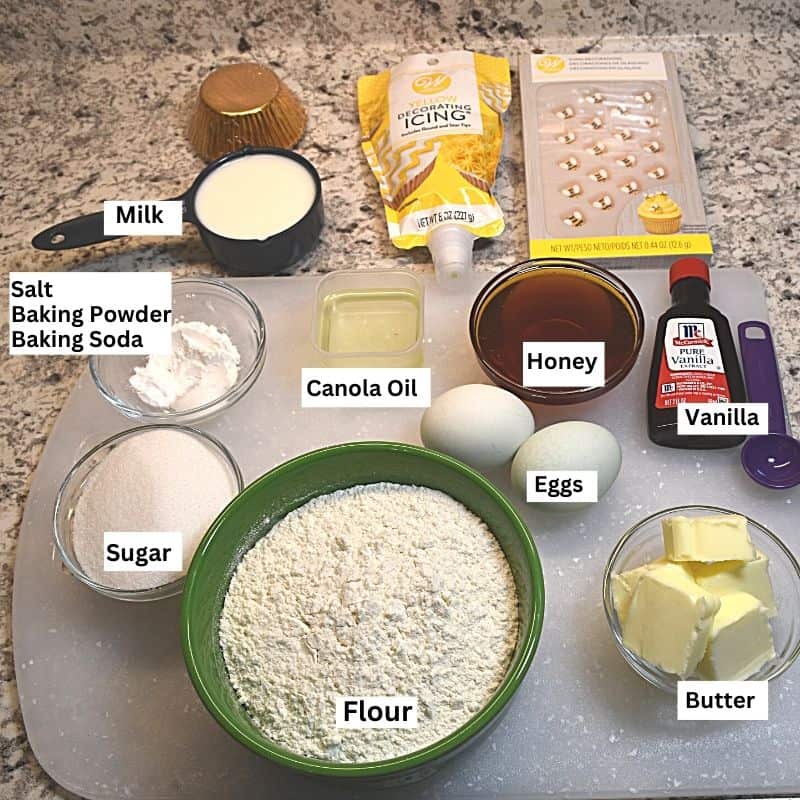 Labeled ingredients needed to bake and decorate bee cupcakes with honey .