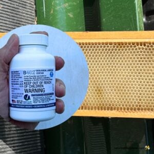 Liquid bottle of certan B402 wax moth control and a frame of comb.