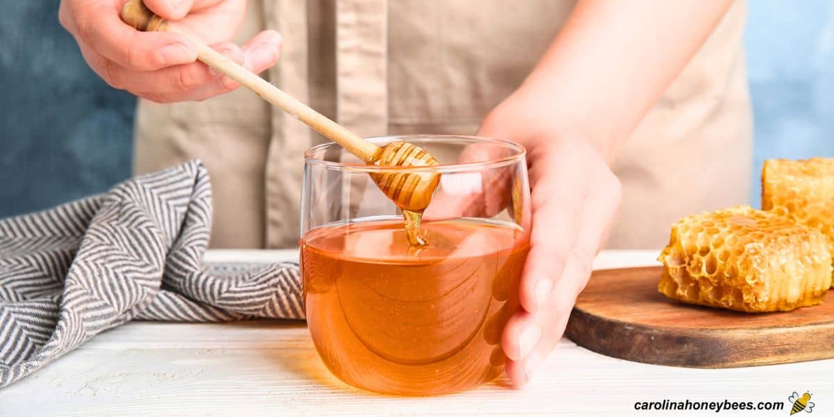 Cook dribbling honey into a glass container for use in recipes.