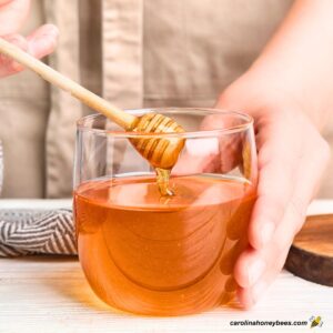 Measuring honey for healthy recipes using a wooden dipper.