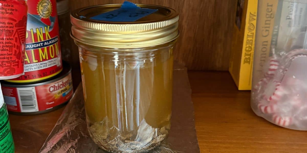 Raw propolis and alcohol in a sealed jar sitting in a dark pantry.
