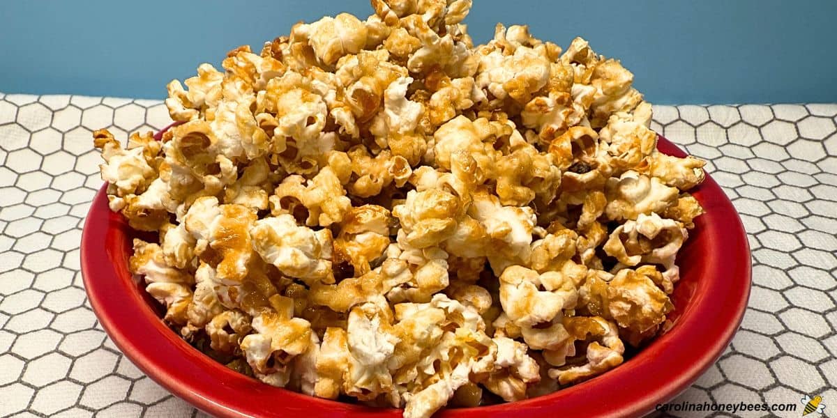 Homemade popcorn with honey coating in red bowl.