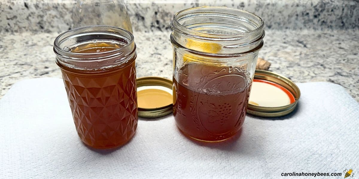 Two glass jars containing homemade honey cough syrup with lemon and ginger.